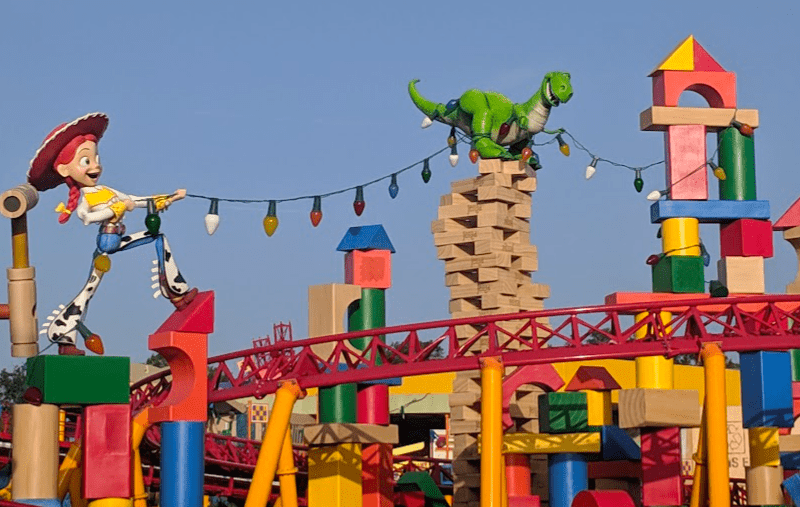 Larger than-life structures of Jessie and Rex holding up colored lights over the track of Slinky Dog Dash in Toy Story Land.