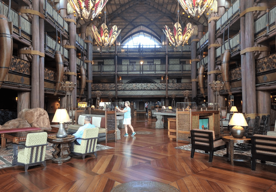 The interior lobby of Disney’s Animal Kingdom Lodge taken from the ground floor and showing multiple levels of hallways. Heavily accented with dark wood and African elements.
