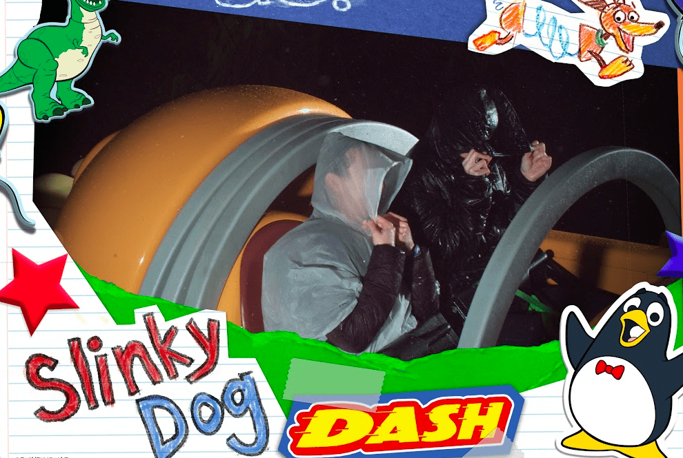 Ride photo of two people dressed in warm clothing and ponchos with their hoods pulled up to obscure their faces riding Slinky Dog Dash. It looks wet and cold. 
