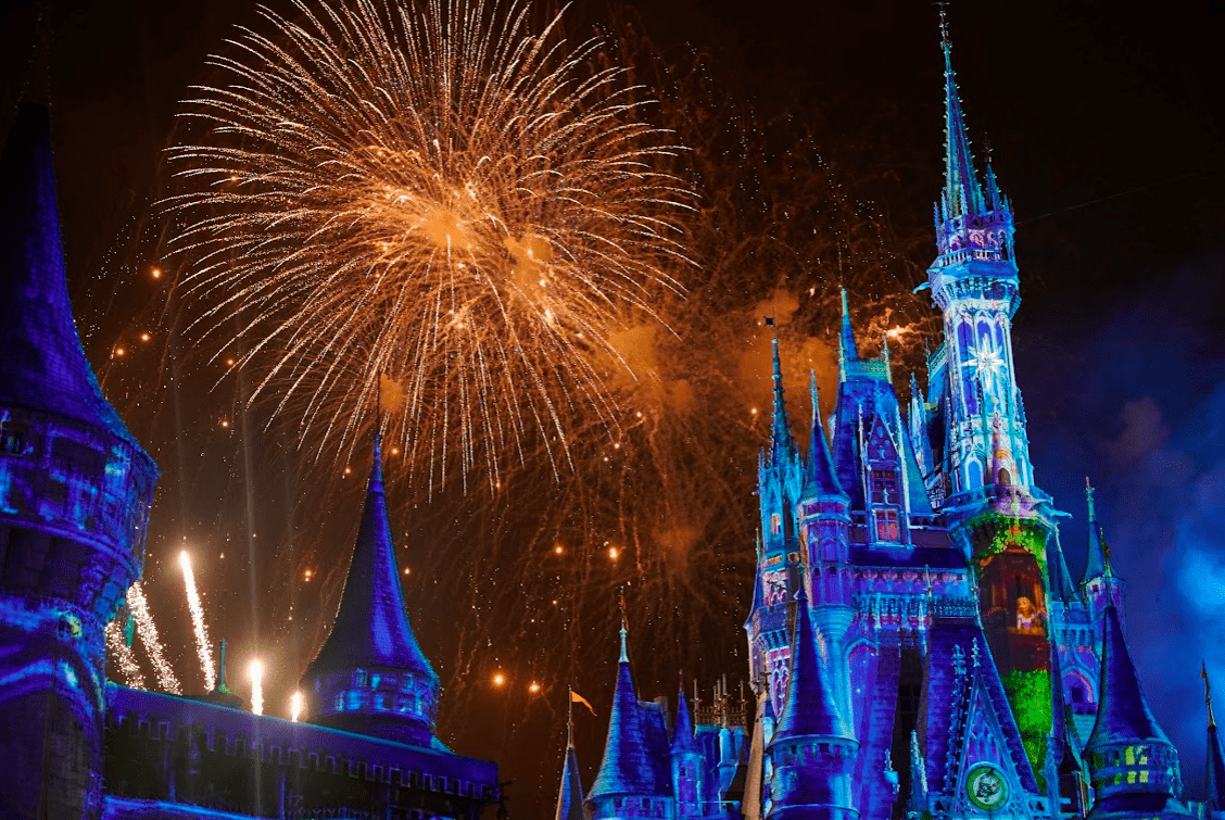 Close-up view of Cinderella Castle projections on the left side with fireworks in background.