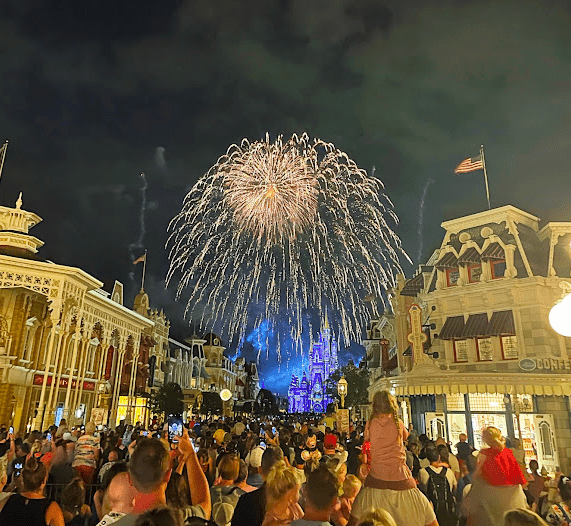 Fireworks over Cinderella Castle and Main Street USA, taken from far back on Main Street. Heavy crowds in the foreground.