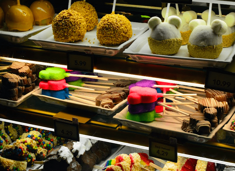 Dozens of Disney-themed and Mickey-shaped sweet treats in a glass pastry case. 