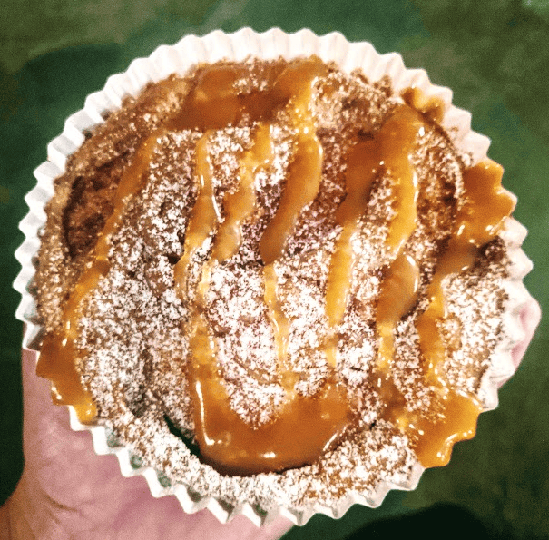 Caramel drizzle and powdered sugar on top of an apple cake.
