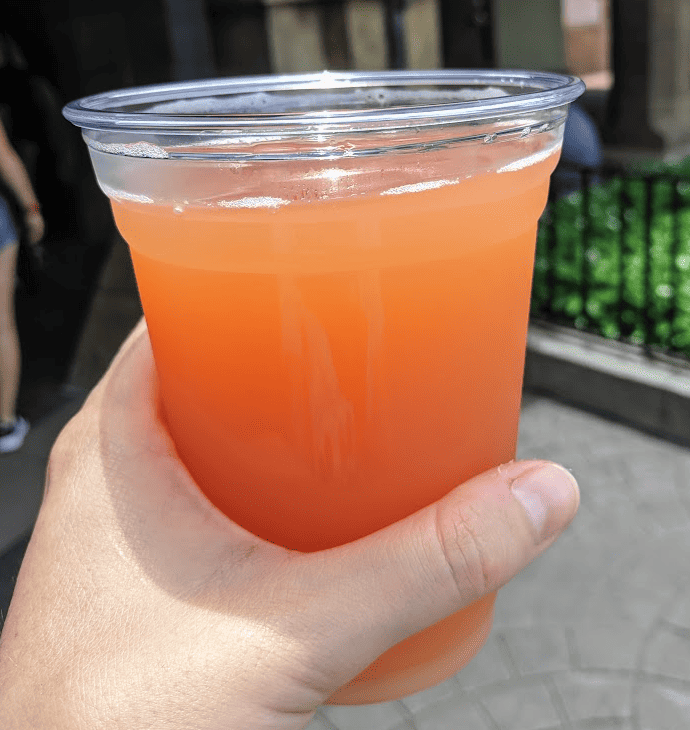 Hand holding a light orange-pink colored grapefruit beer.