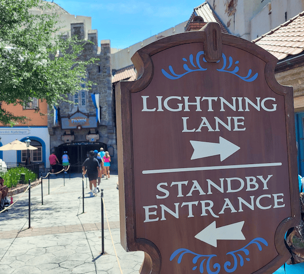 A sign in front of the Frozen Ever After ride designating which way the Lightning Lane and Standby lines start.
