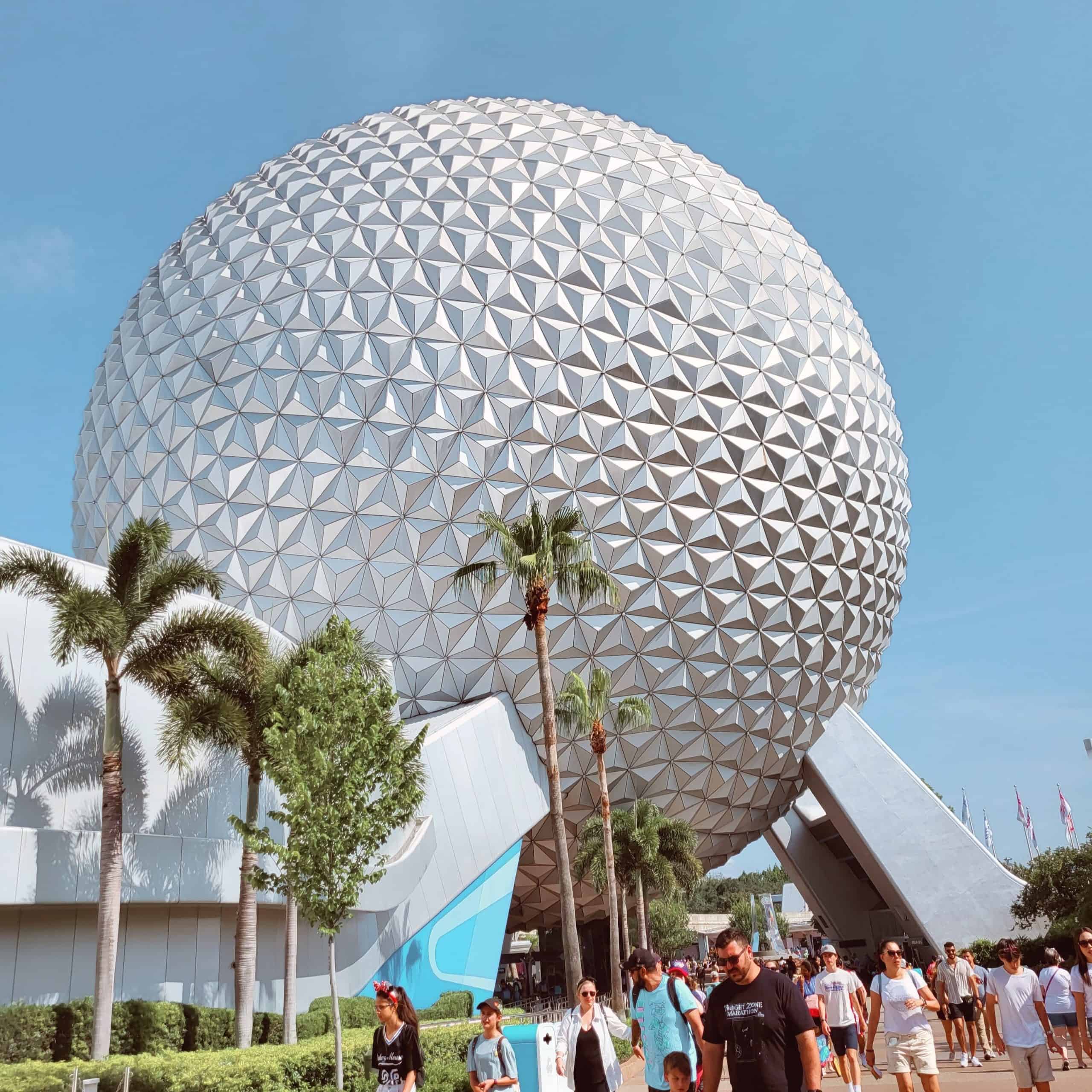 EPCOT Spaceship Earth ball with palm trees on a sunny day
