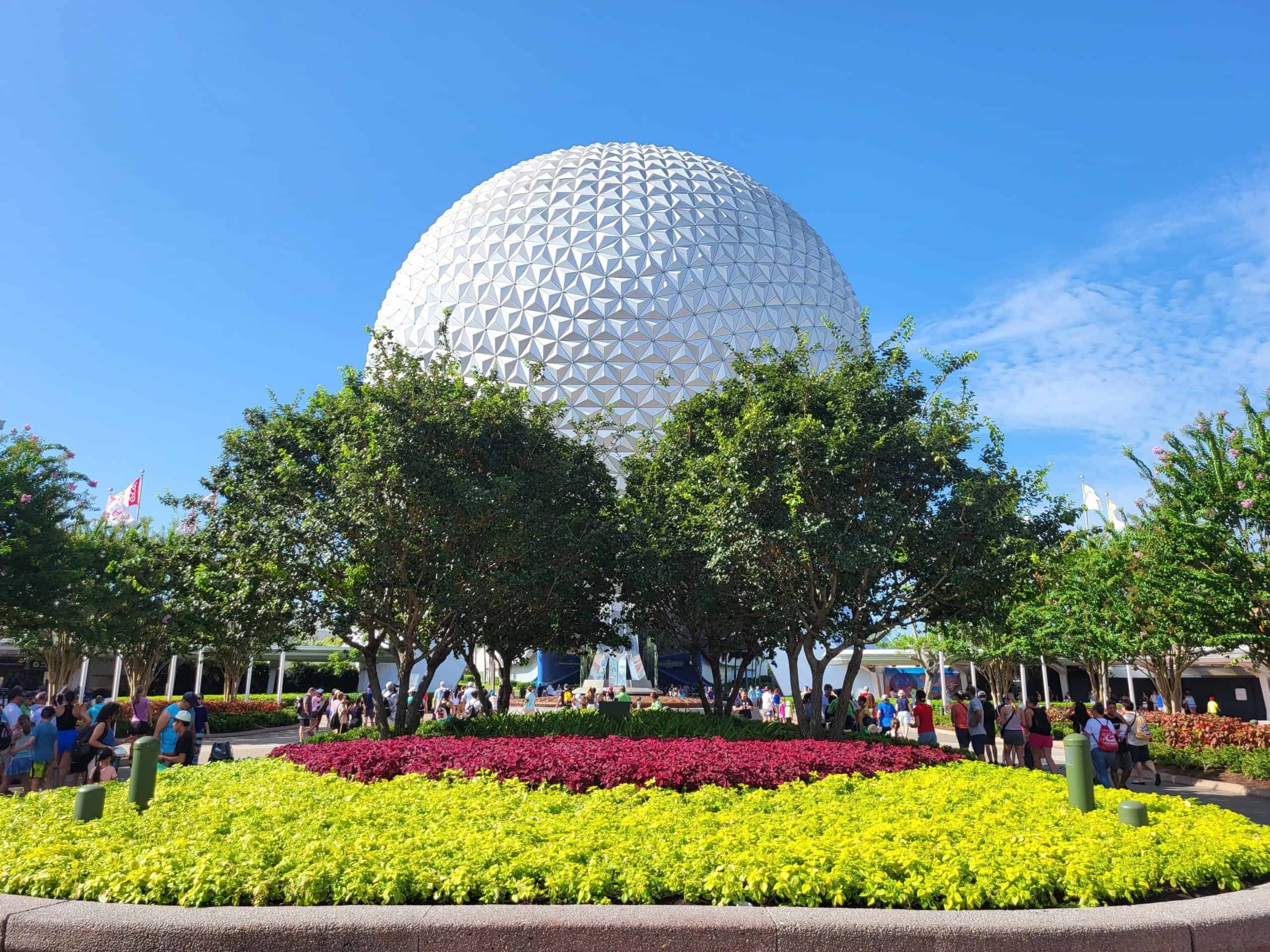 Entrance of EPCOT on a sunny day with gardens looking at Spaceship Earth