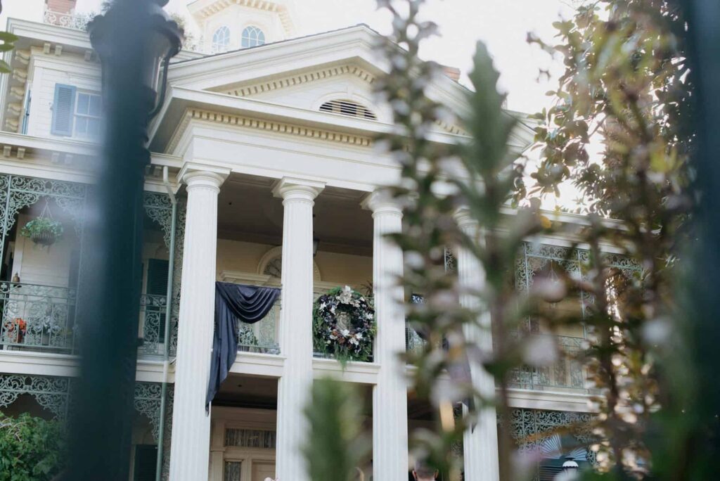 Photo of outside of Haunted Mansion in Disneyland, building with large white columns and colonial look
