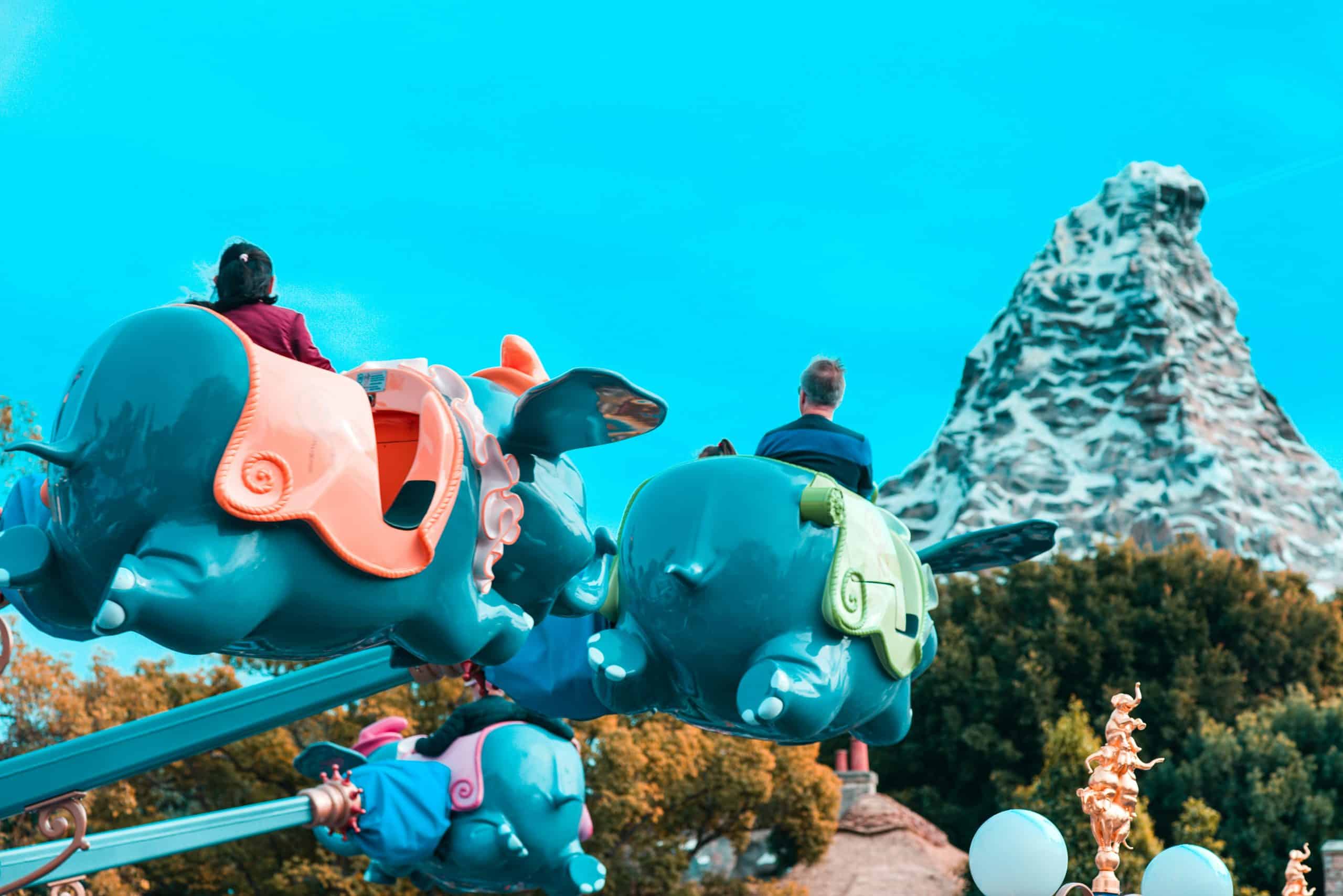 People riding Dumbo at Disneyland with Matterhorn in the background